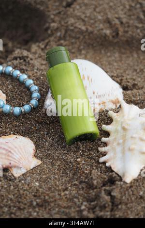 Bottiglia verde posizionata su una spiaggia sabbiosa con conchiglie Foto Stock