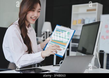 Giovane donna d'affari dipendente professionale che utilizza un pc per l'analisi del banking online sul posto di lavoro. Donna d'affari asiatica di mezza età che lavora su laptop com Foto Stock