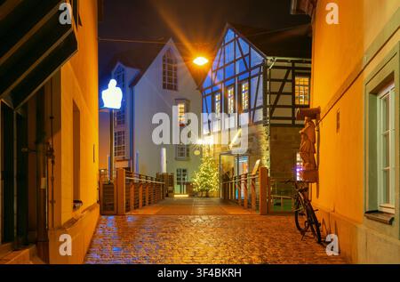 Vista notturna di edifici tradizionali in legno a graticcio, strade illuminate e un albero di Natale decorato nel centro storico di Bamberg, Bavaria, Germ Foto Stock