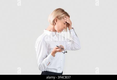 Imprenditore overlavored che soffre da emicrania, affaticamento o che ha problema su sfondo chiaro Foto Stock