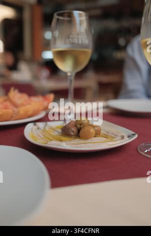 Tapas spagnole tradizionali servite in un ristorante locale, con acciughe marinate (boquerones), olive miste condite con olio d'oliva e vino. Foto Stock