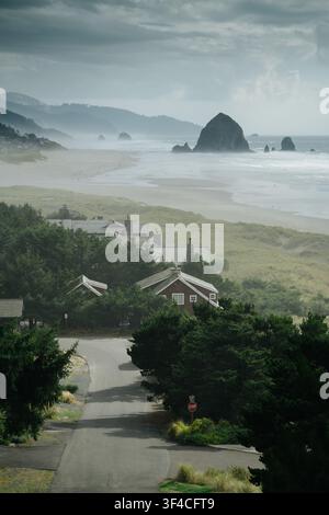 Case costiere di Cannon Beach con Haystack Rock sullo sfondo in una giornata cupa, Oregon, Nordovest Pacifico, USA Foto Stock