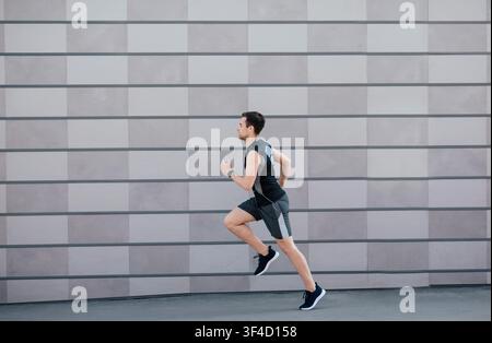 Allenamento cardio. Uomo con bel corpo in abbigliamento sportivo jogging in città Foto Stock