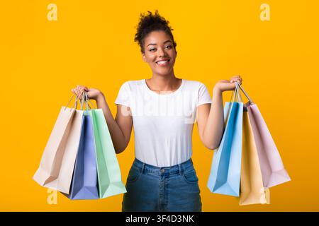 Ritratto di allegra donna nera che tiene borse per lo shopping Foto Stock