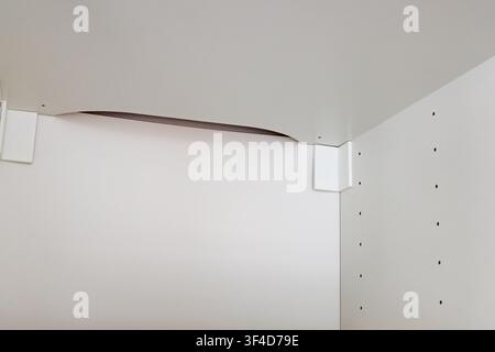 Questa immagine evidenzia un angolo di un armadio moderno con un design senza giunzioni e hardware nascosto Foto Stock