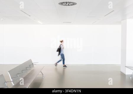 Motion Blur di donna a piedi la contemporanea vuoto bianco corridoio. Foto Stock