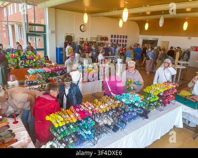 Helsingborg, Svezia: un mercato di artigianato e lana in una fiera creativa, con tavoli ricolmi di gomitoli di lana colorati e visitatori che curiosano. Banco Foto Stock