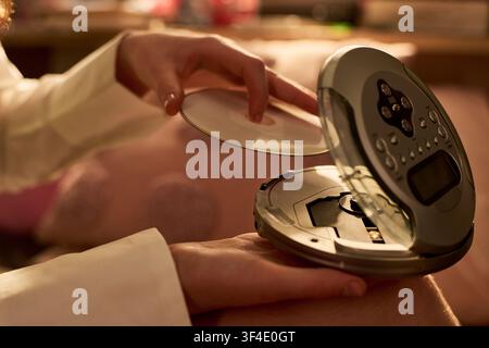 Donna adulta che inserisce un CD in un lettore portatile per l'uso audio domestico Foto Stock