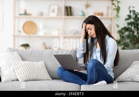 Giovane donna freelance coreana con problemi con il laptop a casa Foto Stock