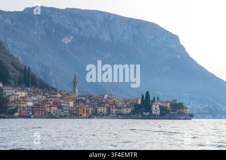 Vista della città storica di Varenna con i suoi edifici colorati e il campanile appollaiato contro il ripido fianco della montagna sulle rive del Lago di Como Foto Stock