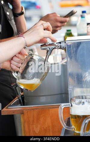 Barista che versa birra in un bicchiere da una macchina, primo piano Foto Stock