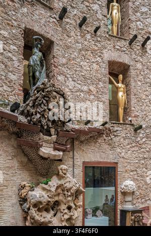 Cortile surrealista del Teatro-Museo Dalí a Figueres, in Spagna, con sculture grottesche e manichini dorati su muri di pietra. Foto Stock