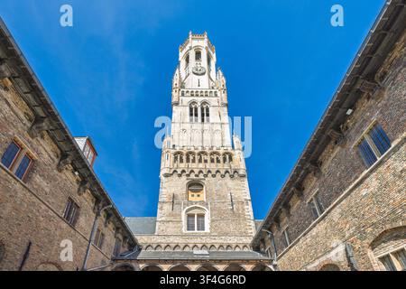 Il Campanile di Bruges, una torre medievale in pietra nella città di Bruges in Belgio, Europa. Vista ad angolo basso di un'antica torre in pietra tra mattoni storici Foto Stock