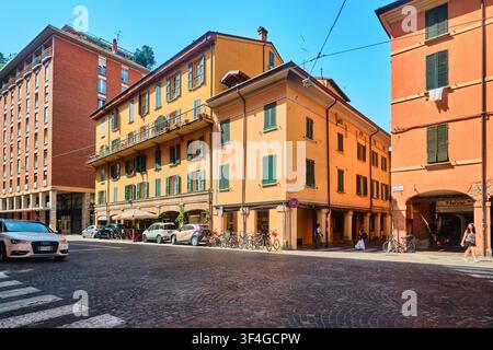 Bologna, Italia – Maggio 2026: Vista d'angolo di edifici residenziali tradizionali colorati con portici e vita di strada Foto Stock