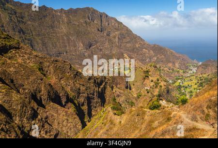 Vista aerea della Trilha do Vale do Paul con aspre montagne vulcaniche, una valle verdeggiante, un sentiero escursionistico tortuoso e l'Oceano Atlantico a Faja Foto Stock