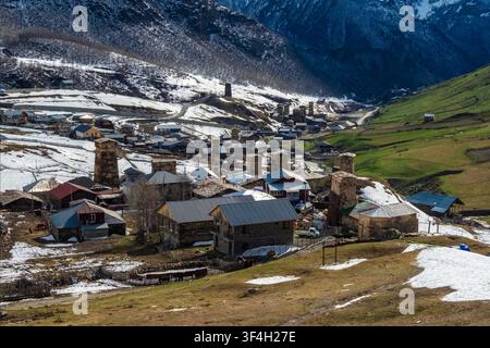 Il villaggio di Ushguli, situato nella regione di Svaneti in Georgia, è una gemma innevata incastonata tra le montagne. Le sue case in pietra con tetti rossi si aggrappano al terreno in pendenza, e antiche torri si ergono sopra le modeste abitazioni. Erba selvatica e una pa persistente Foto Stock