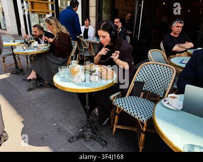Parigi, Francia - 14 maggio 2026: Le persone mangiano e bevono in un vivace caffè sul marciapiede di Parigi per un momento rilassato di pranzo urbano. Foto Stock