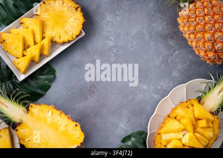 Vista dall'alto della fetta rotonda di ananas dolce e frammenti su una tavola di legno su sfondo grigio scuro. Foto Stock
