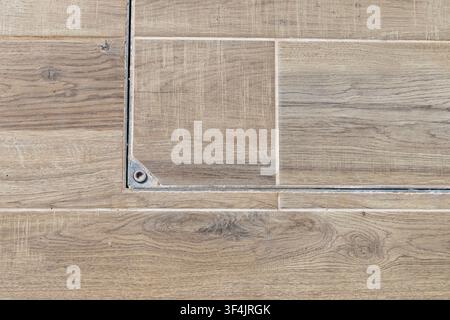 Texture dettagliata di assi di legno invecchiate e piastrelle di ceramica, con una grata metallica sottile e un dettaglio di vite Foto Stock