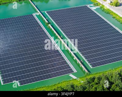 Vista aerea della centrale solare galleggiante dell'impianto di trattamento delle acque reflue di Sloka con file di pannelli solari su uno stagno verde a Jūrmala, Lettonia. Foto Stock