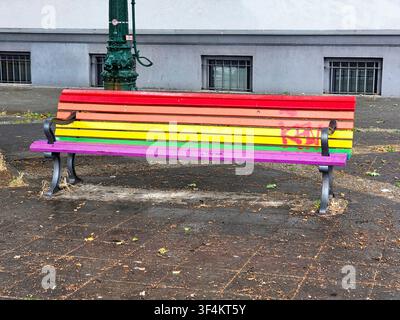 Colori vivaci; panchina stradale in legno dipinta nei colori dell'arcobaleno nel Nollendorfkirz, Regenbogenkiez, Berlino, Germania Foto Stock