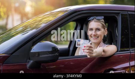 Donna felice che mostra la patente dal finestrino dell'auto dopo aver superato l'esame di guida. Banner con spazio per il testo Foto Stock