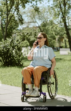 Donna con disabilità che parla al telefono con lo smartphone nel parco Foto Stock