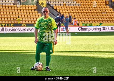 Un uomo con sindrome di Down in una divisa da calcio verde, in piedi con un pallone su un campo da calcio all'interno dello stadio Carrow Road di Norwich durante un evento comunitario Foto Stock