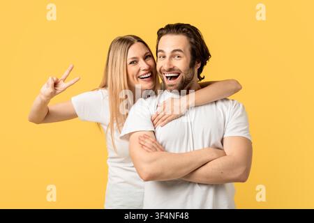 Uomo e donna caucasici sorridenti che posano insieme, sfondo giallo Foto Stock