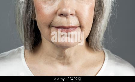 Donna anziana con capelli grigi che sorride e sembra calma, concetto di assistenza sanitaria Foto Stock