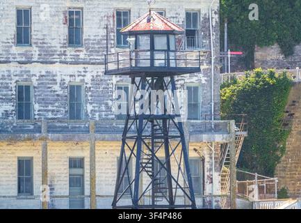 Torre di guardia storica in acciaio che si staglia contro la facciata in pietra consumata dell'ex penitenziario di Alcatraz Island nella baia di San Francisco. Foto Stock