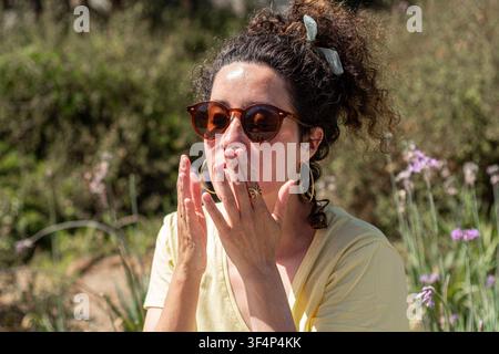 Donna che applica la crema solare sul viso per proteggersi dal sole Foto Stock
