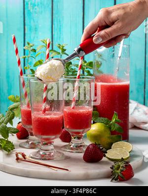Bicchieri di daiquiri alla fragola appena versato con gelato alla vaniglia aggiunto Foto Stock