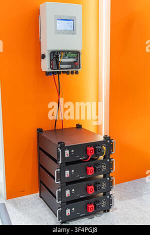 Sistema invertitore domestico con backup a batteria, che mostra unità di potenza modulari, pannello di controllo digitale, sfondo arancione, striscia di luce bianca, linee pulite, cont Foto Stock