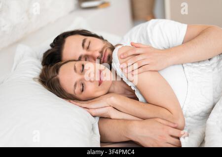 Coppia che dorme insieme a letto, giovane donna e uomo, atmosfera accogliente e rilassata Foto Stock