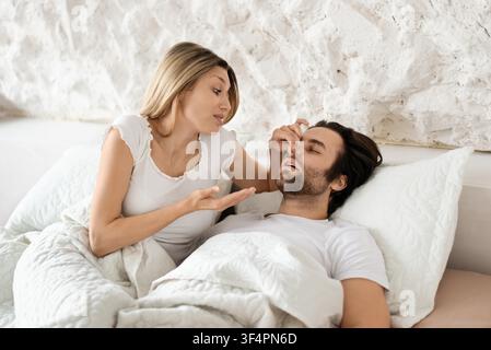 Donna preoccupata che discute i problemi con un uomo a letto, routine mattutina Foto Stock