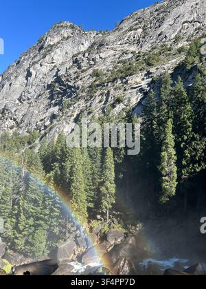 Vernal Fall con un arcobaleno nella nebbia, circondato da scogliere di granito e foresta nel Parco Nazionale di Yosemite, California, USA. Foto Stock