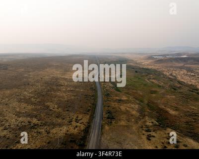 Un piano dall'alto rivela una strada stretta che attraversa vaste pianure Foto Stock
