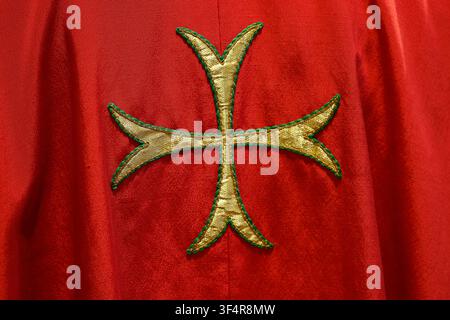 Chiesa Collegiata di Saint-Jacques. Dettaglio di una croce maltese ricamata in oro e verde su un tessuto liturgico rosso acceso. Foto Stock