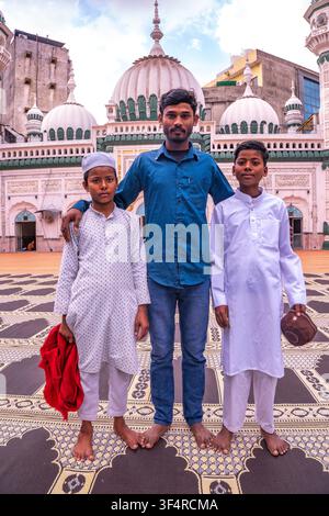Un uomo e due ragazzi sono in piedi davanti alla Grande Moschea Jama Masjid Khairuddin ad Amritsar, Punjab, India. Sono in piedi su un tappeto da preghiera in t Foto Stock