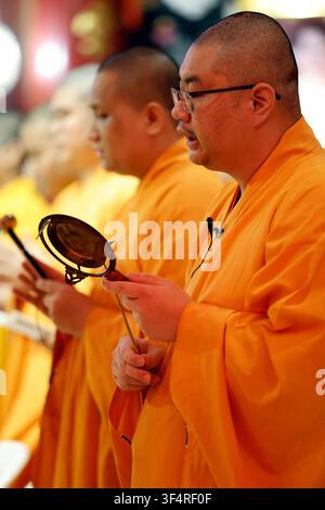 Wat Mangkon Kamalawat, o il Tempio del Drago e del Loto. Monaci buddisti, vestiti con abiti arancioni brillanti, stanno partecipando a una cerimonia religiosa Foto Stock