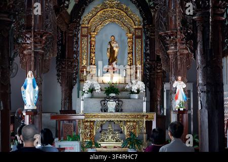 Cattedrale di Phat Diem. Una cappella presenta un altare riccamente decorato con statue di santi e ornamenti religiosi. I fedeli sono in preghiera. Phat Diem Foto Stock