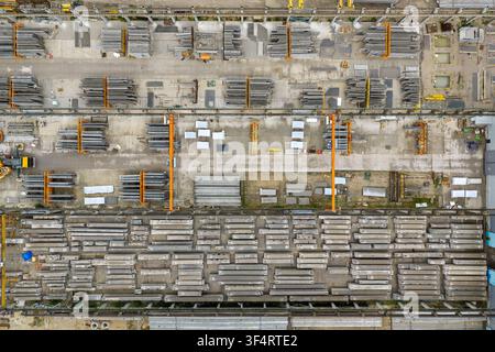 Vista aerea di un cantiere di produzione di elementi in cemento precompresso con file di travi impilate, gru industriali sospese e aree di stoccaggio organizzate a Po Foto Stock