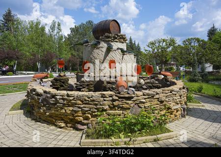 Fontana in pietra decorata con brocca e bicchieri d'acqua rossi in un giardino, fontana con bottiglie di vino che riempiono i bicchieri, Cantina Milestii Mici, Milestii Mici Foto Stock