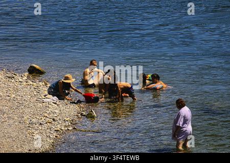 Gruppo familiare che gioca e si rilassa sulla riva poco profonda del fiume nell'acqua, balneazione urbana, Reno, attività ricreative, Rheinbord Basel, Cantone di Baselsta Foto Stock