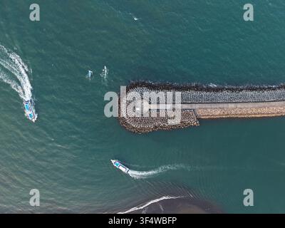 Vista aerea del porto di Sanur con barche che navigano vicino al frangiflutti nelle acque turchesi di Kecamatan Denpasar Selatan, Bali, Indonesia. Foto Stock