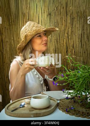 Donna che assapora una tazza di caffè in un accogliente caffè Foto Stock
