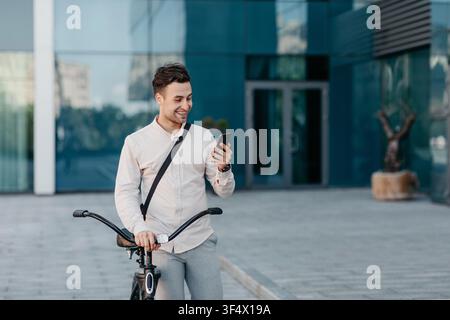 Ritratto esterno di bel giovane uomo con telefono cellulare e. bicicletta in strada Foto Stock