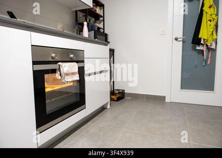 Interno di cucina moderna con forno incorporato che cuoce o riscalda attivamente il cibo Foto Stock