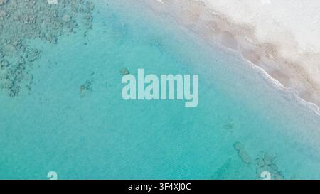 Vista aerea dall'alto di acqua di mare turchese chiara che incontra una spiaggia di sabbia chiara con onde gentili in Grecia per le vacanze estive, sfondo foto stock natura Foto Stock